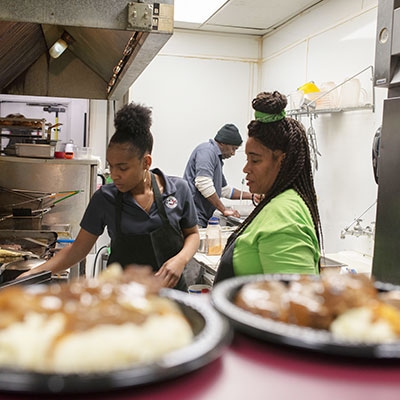 Glory Wells (left) takes inventory, seasons vegetables, grills catfish, washes dishes and wipes down tables at Wanda J’s Next Generation. 