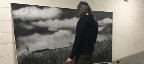 Joe Andoe stands in front of one of his landscape pieces in his Brooklyn studio