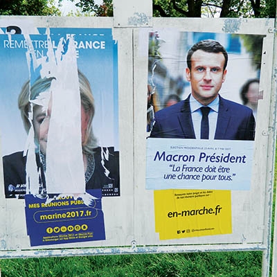 A defaced Marine Le Pen presidential poster next to an Emmanual Macron poster in Amiens, France  