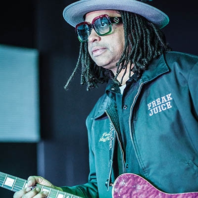 Tori Ruffin, owner of Juicemaker Lounge, plays guitar at the venue sporting a jacket with his band’s name.