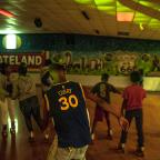 Skaters roll past a mural depicting the original Skateland sign that still stands outside the building. The rink draws up to 500 people from across Tulsa any any given night for skating, games, and concessions.