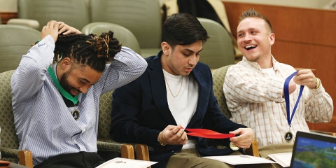 From left: First Step Diversion Program graduates Christopher Davis, Miguel Chavez, and Justin Cathey look over their medals and certificates at the Feb. 21 graduation ceremony at Tulsa County Courthouse